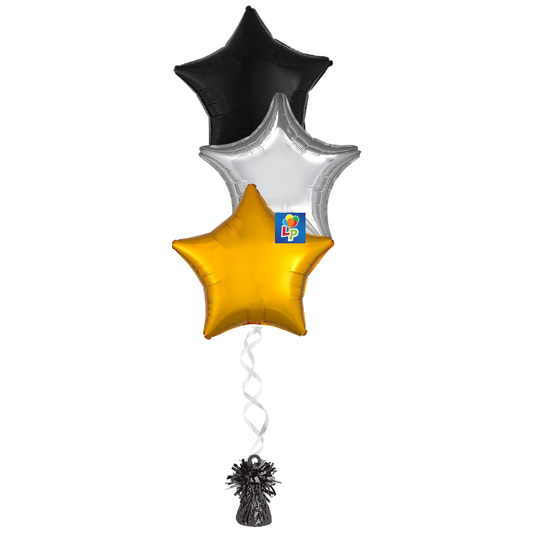 Three star-shaped foil balloons in black, silver, and gold, tied together with a white spiral ribbon and a small black balloon weight to match.
